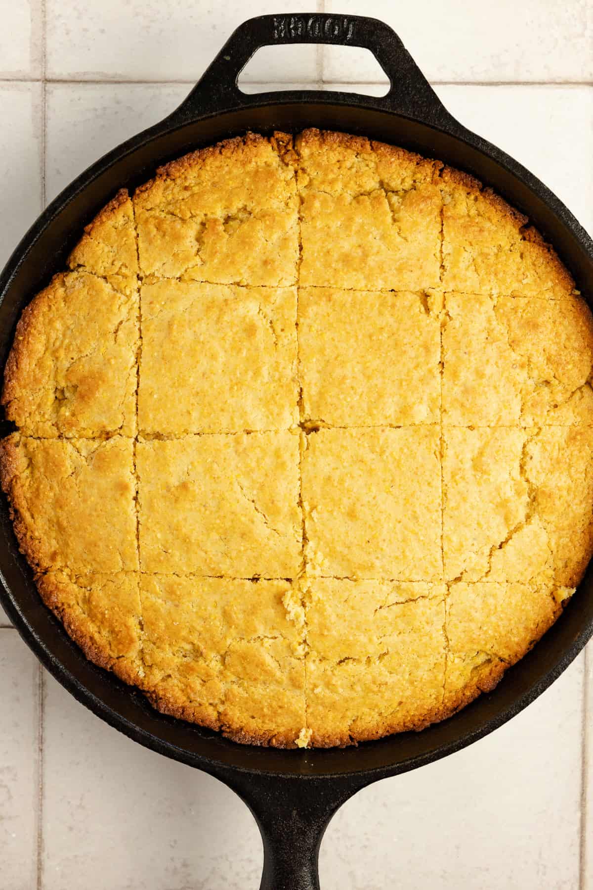 Cornbread in a cast iron skillet cut into squares.