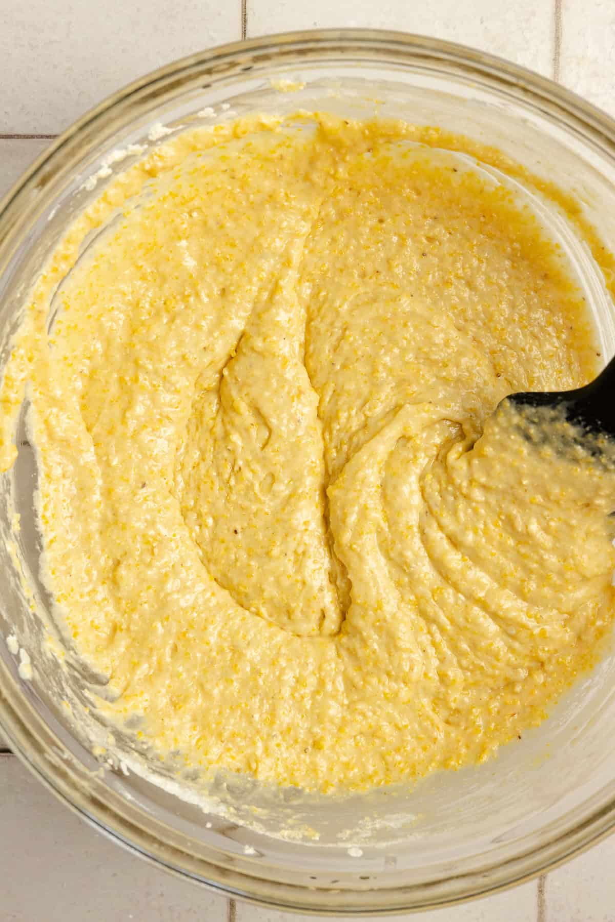 Cornbread batter mixed in a bowl with a spatula.