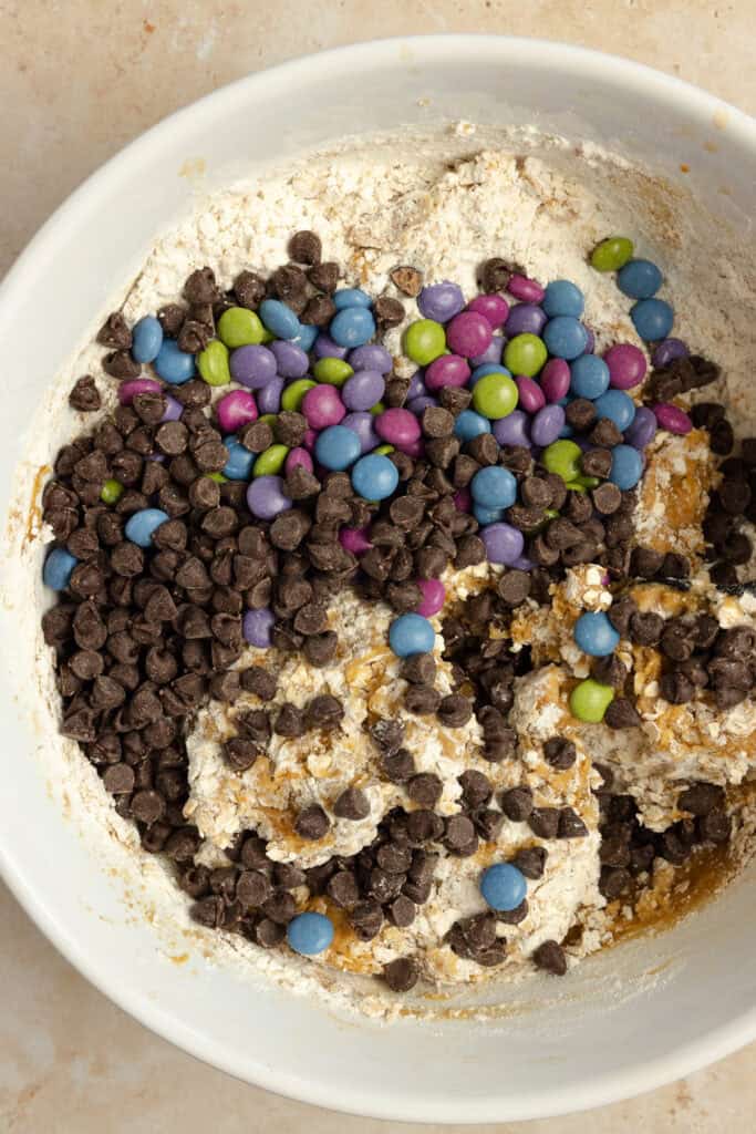 Chocolate chips and candy added to batter in a bowl.