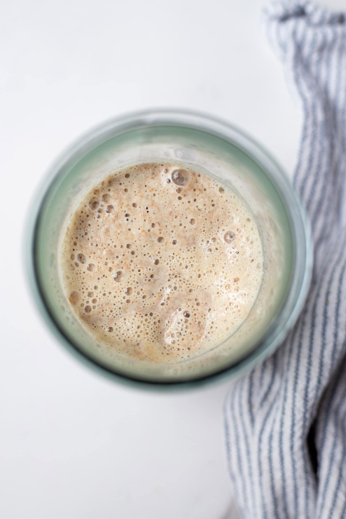 Overhead photo of bubbly spelt sourdough starter in a glass jar.