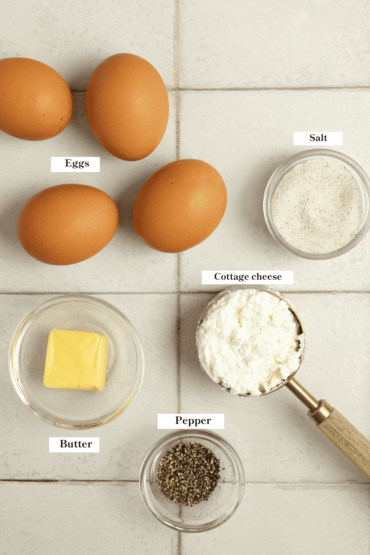 Eggs, butter, cottage cheese, salt and pepper sitting on the countertop.