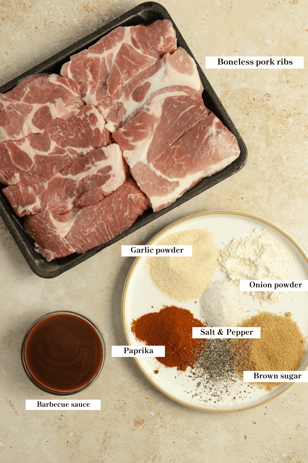 Pork ribs, a plate of seasoning, and a bowl of barbecue sauce on a countertop.