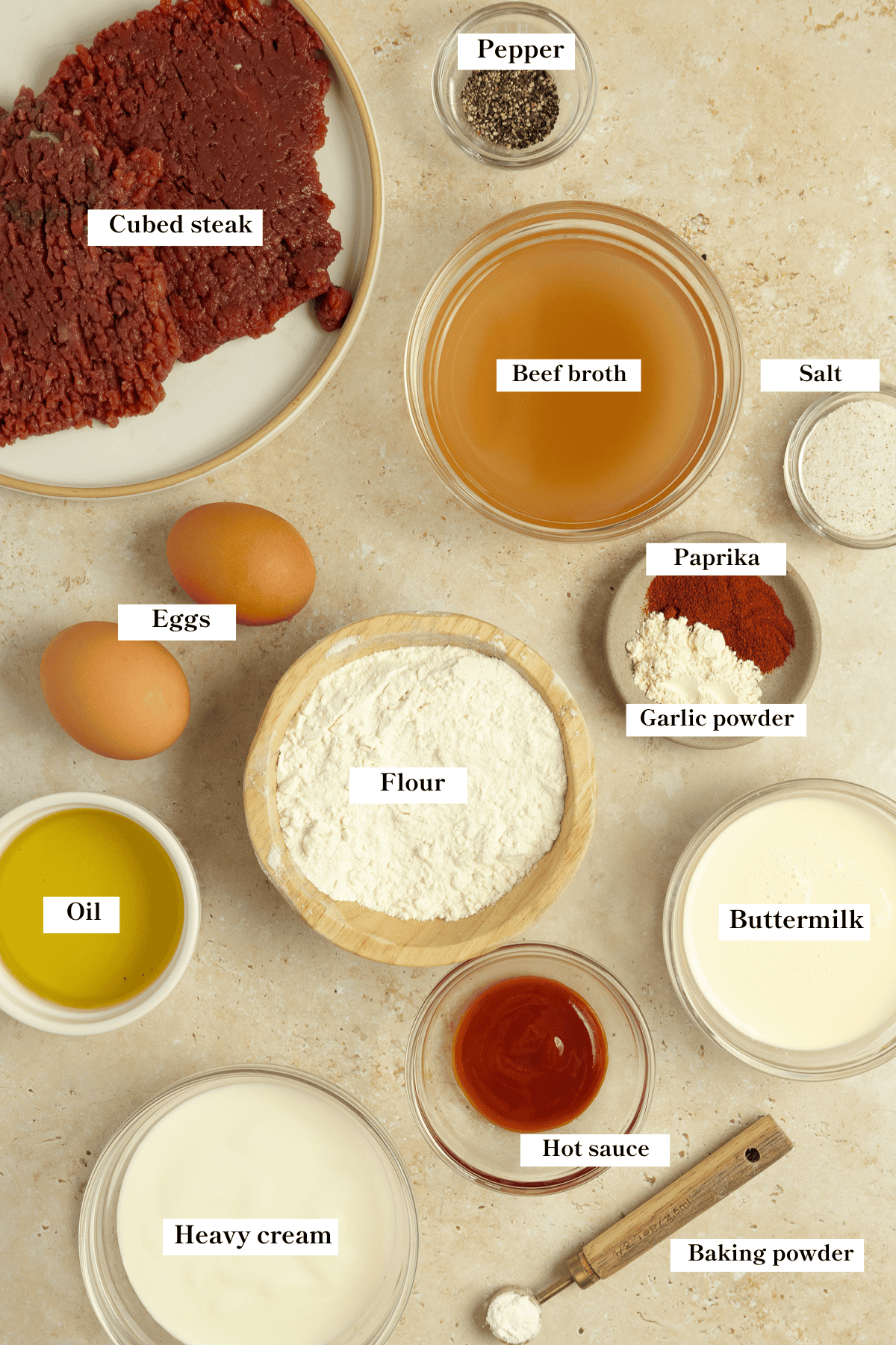 Steak, flour, eggs, seasoning and other ingredients on a countertop.