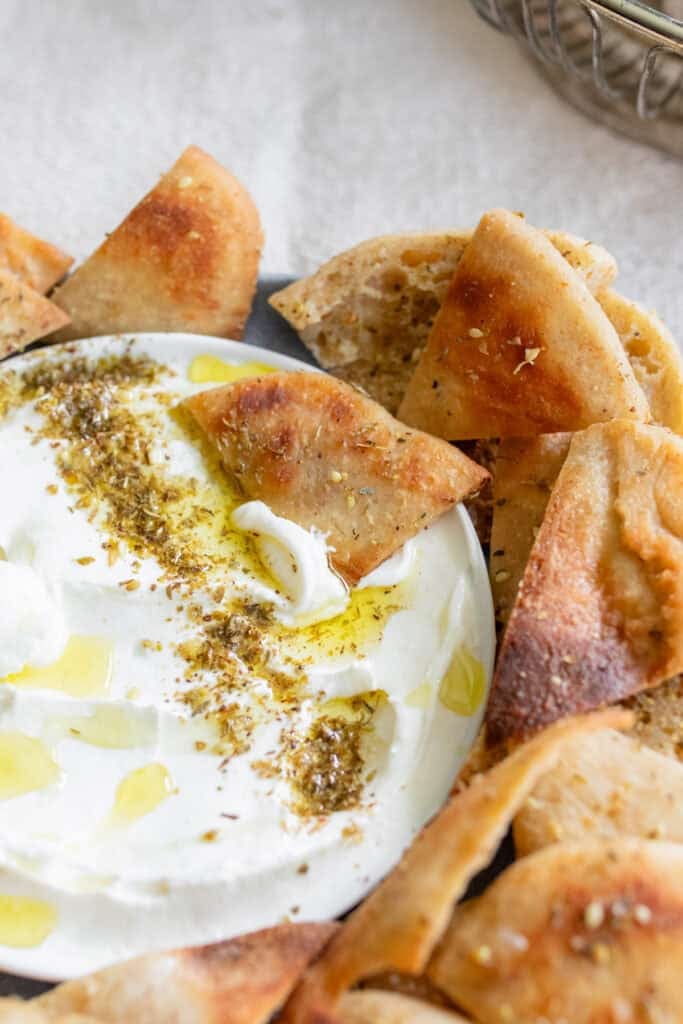 Pita chips layered around a bowl of white dip.