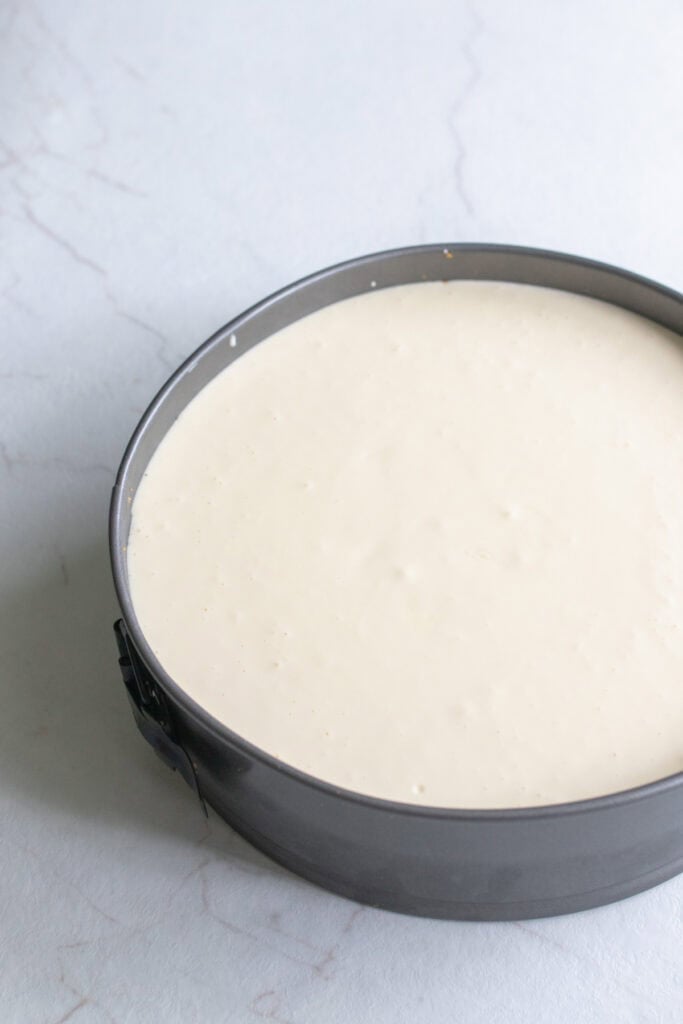 Cheesecake batter in a metal baking dish.