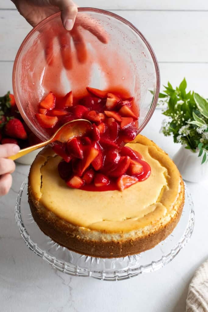Fresh strawberries in strawberry sauce pouring onto a cheesecake.