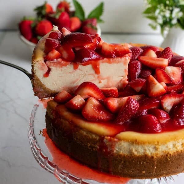 a slice of cheesecake drizzled with strawberries.