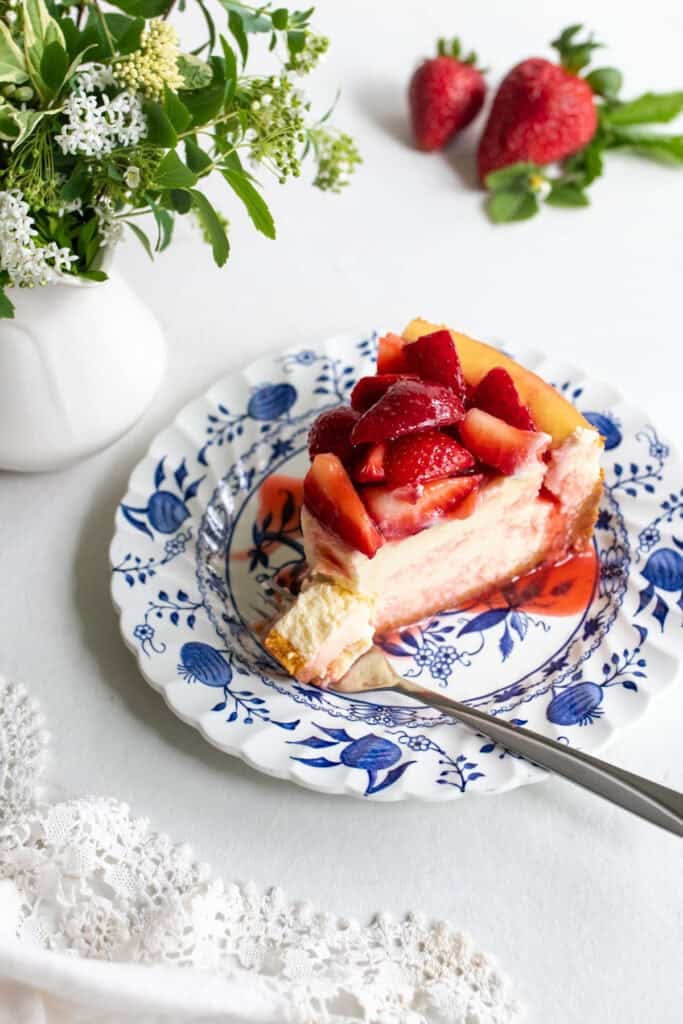 a slice of strawberry cheesecake on a blue and white plate.