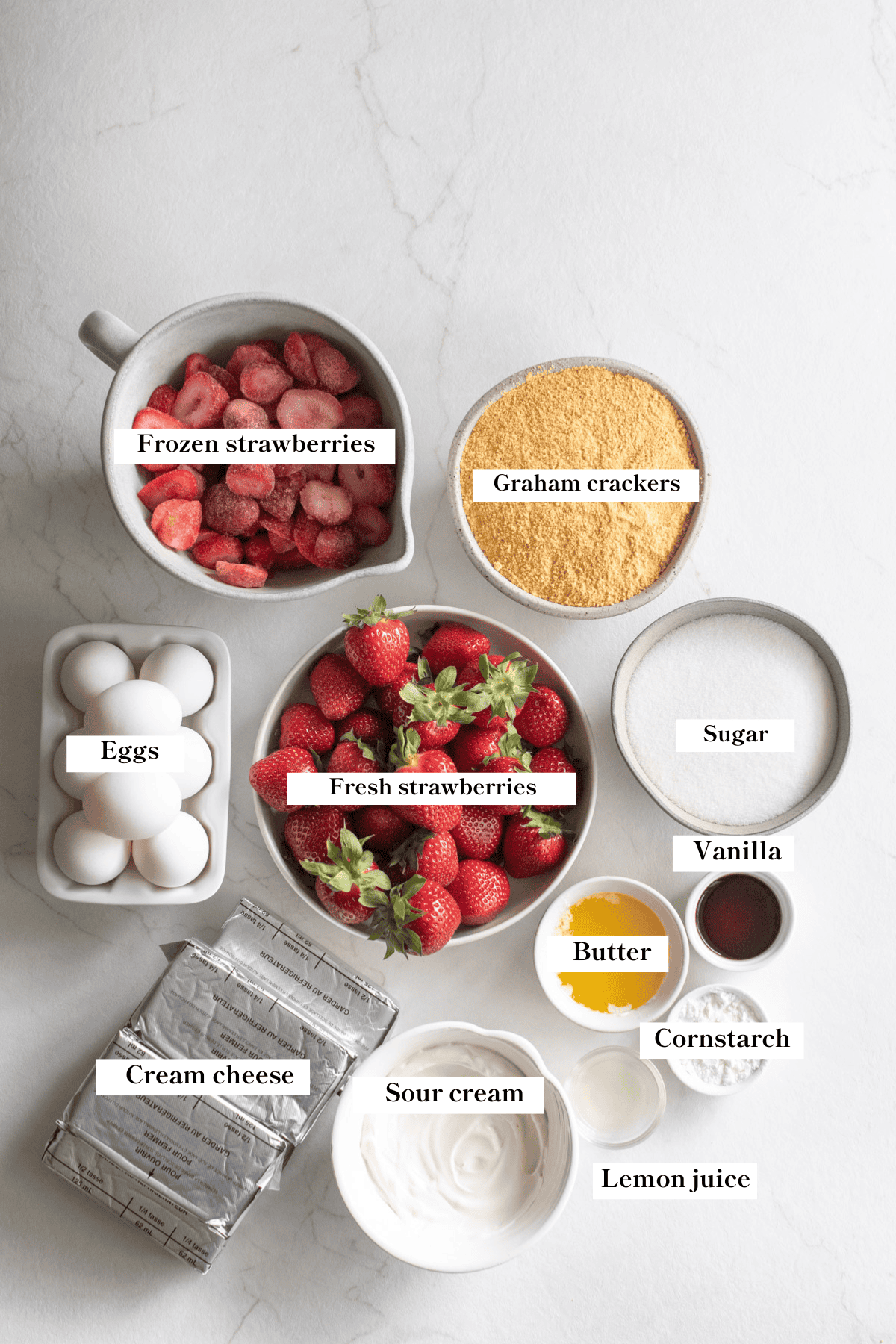 Ingredients for strawberry cheesecake in bowls on the counter.