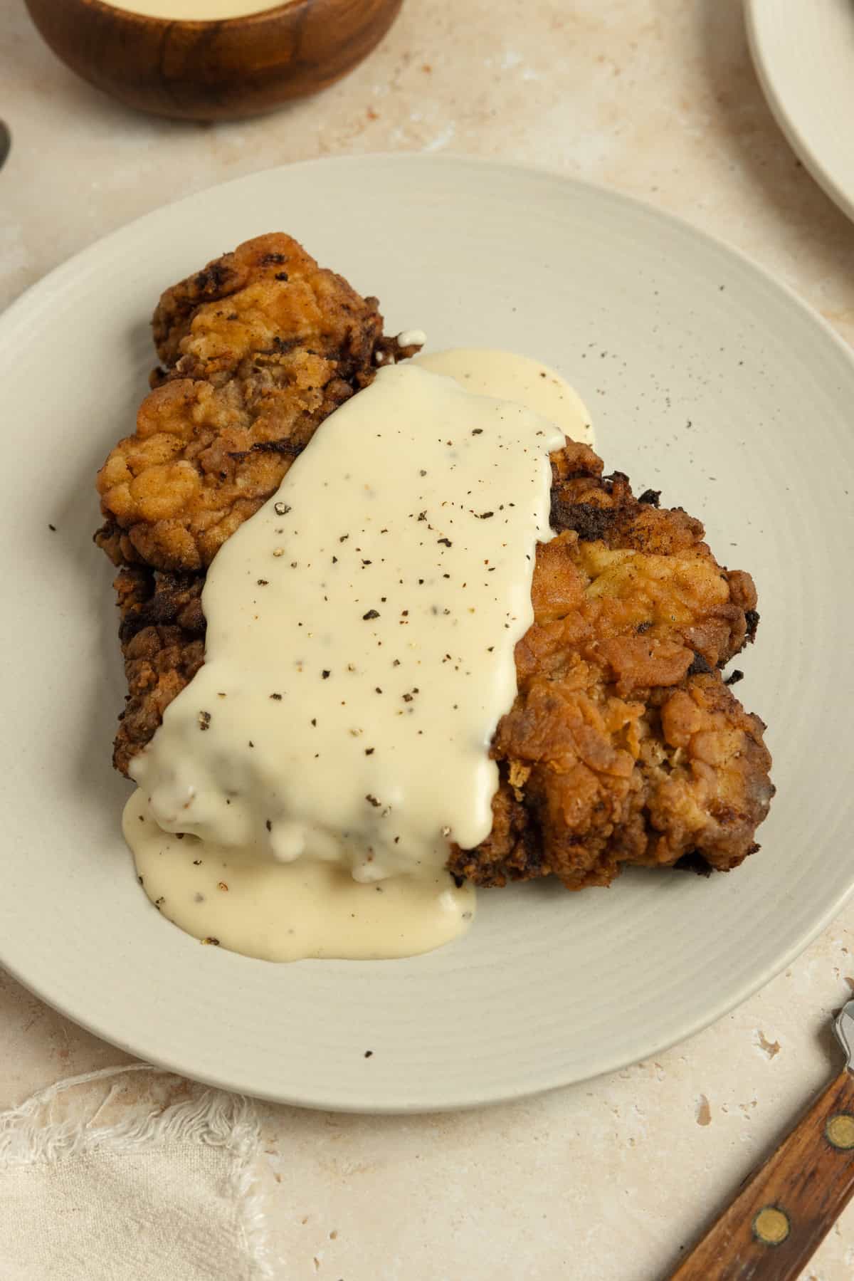 Chicken fried steak topped with gravy on a white plate.