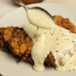 Pouring gravy over chicken fried steak.