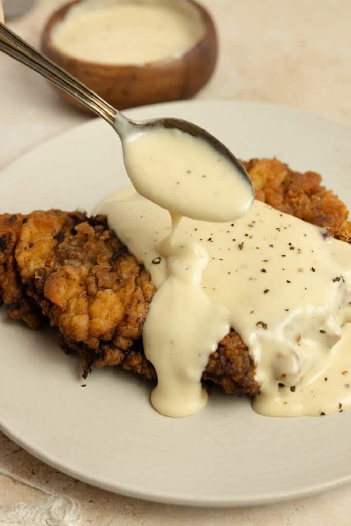 Pouring gravy over chicken fried steak.