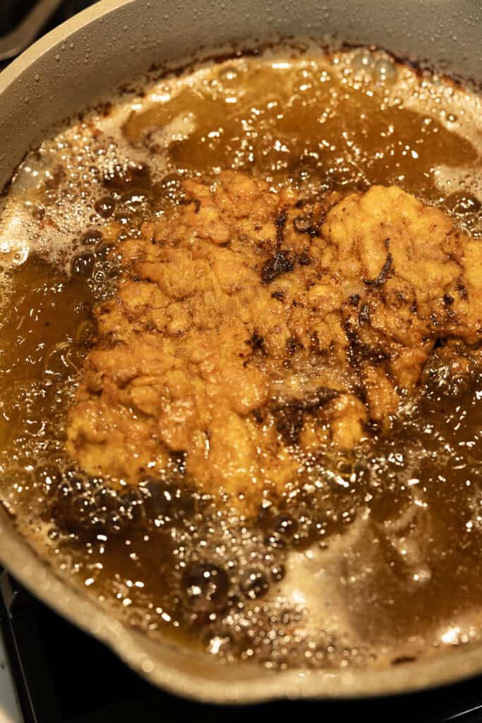 Frying chicken fried steak in a pot with oil.