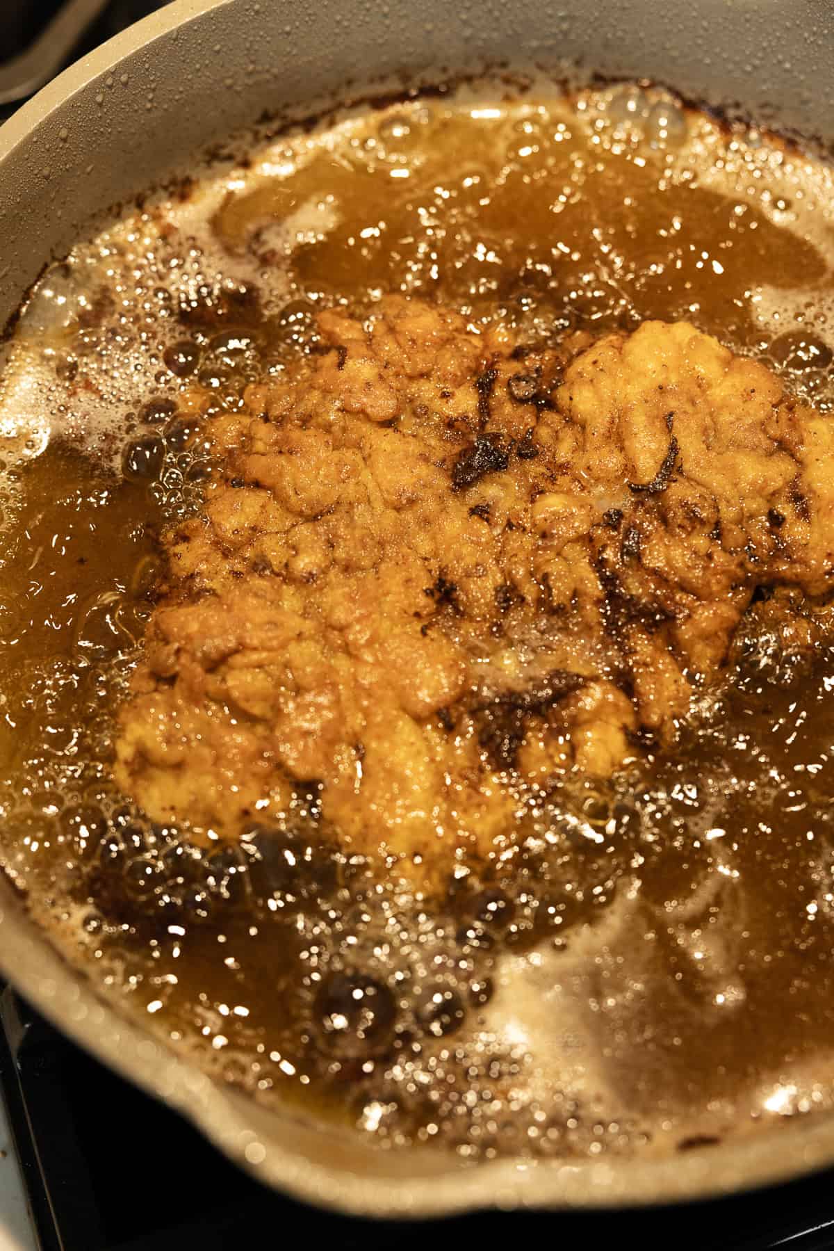 Frying chicken fried steak in a pot with oil.