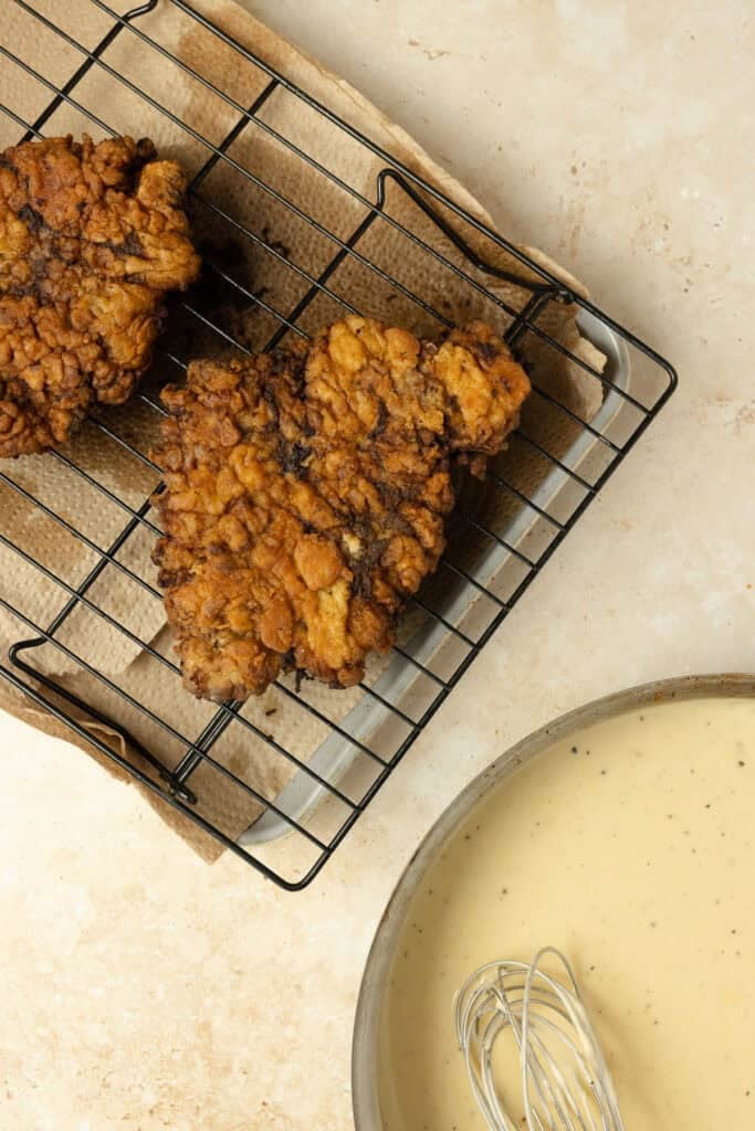Chicken fried steaks on a cooling rack.