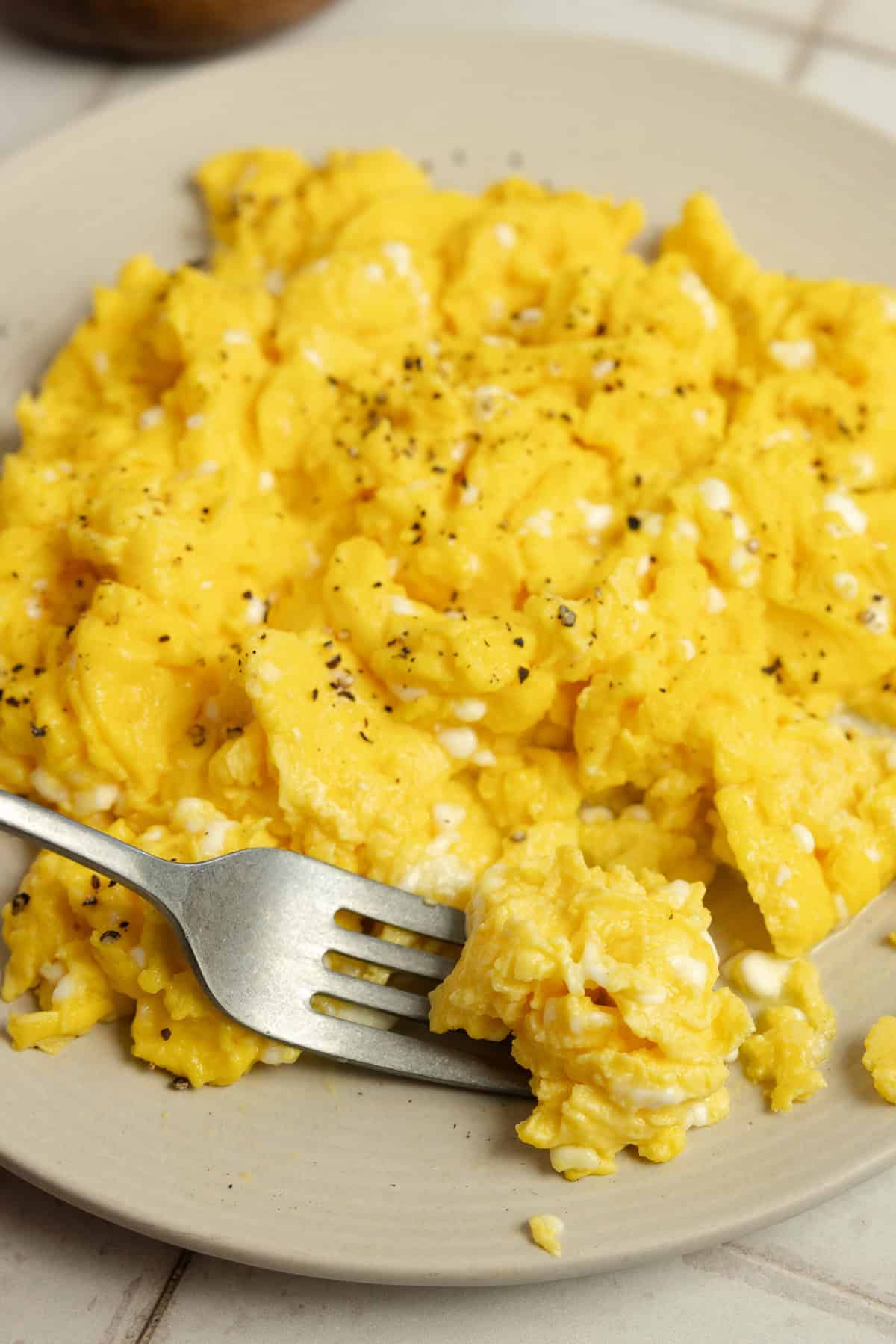 Finished scrambled eggs on a plate with a fork.