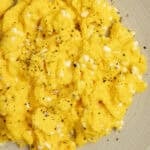 Scrambled eggs on an off white colored plate.
