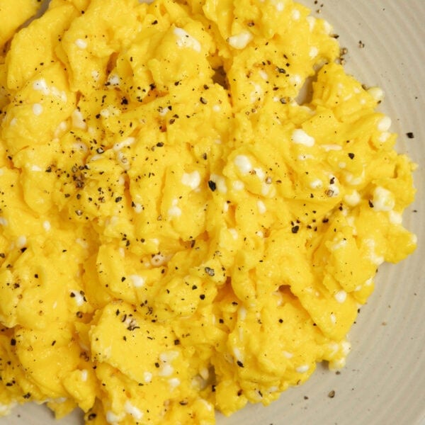 Scrambled eggs on an off white colored plate.