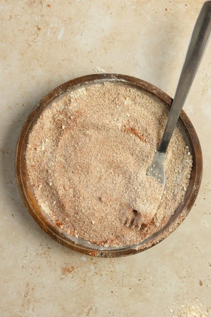 Mixing seasoning together in a bowl with a fork.