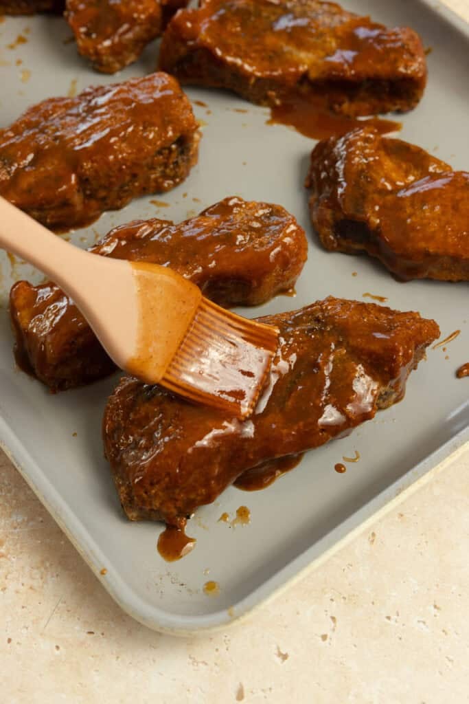 Brushing barbecue sauce on pork ribs.