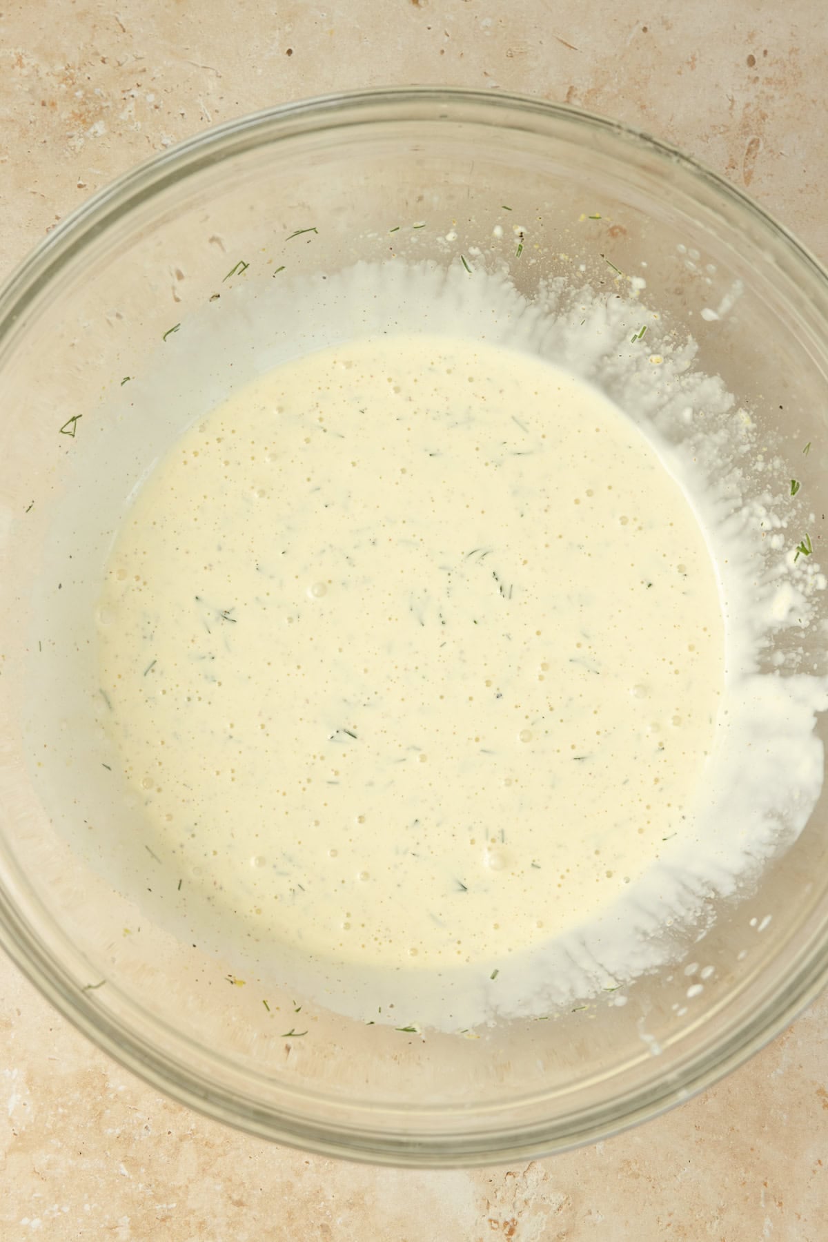Mixing potato salad dressing in a glass bowl.