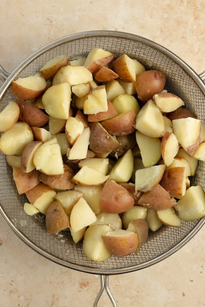 Cooked potatoes in a stainer.