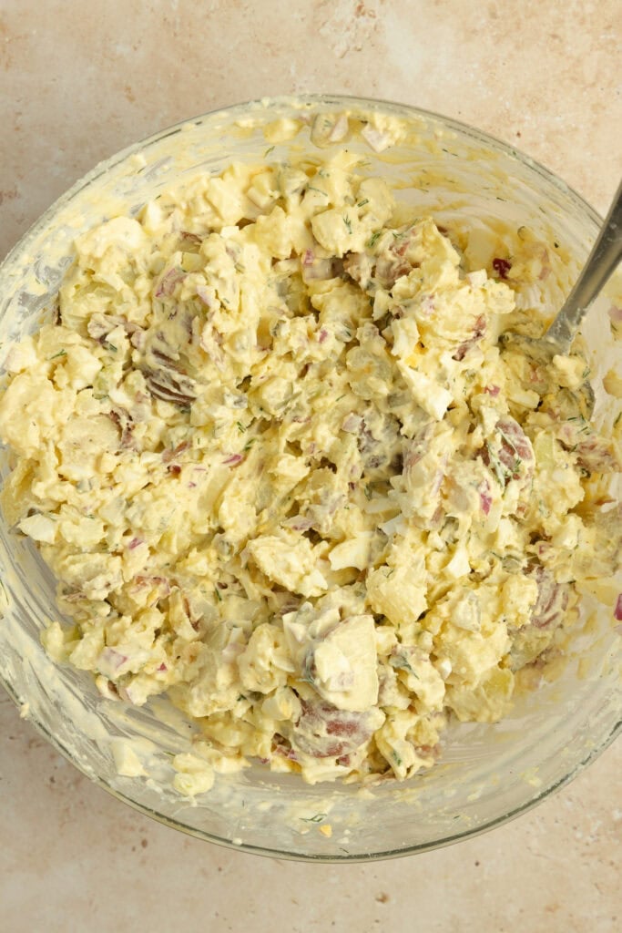 Potato salad mixed together in a glass bowl.