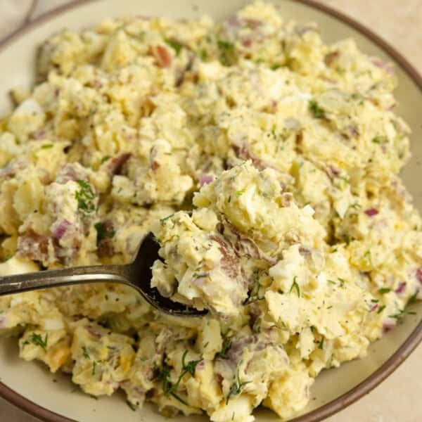 Scooping out a spoonful of dill potato salad in a bowl.