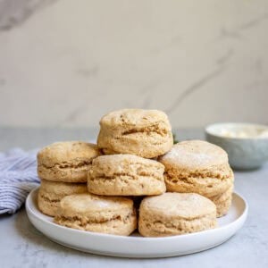 Whole wheat biscuits made with fresh milled flour stacked up on a plate.