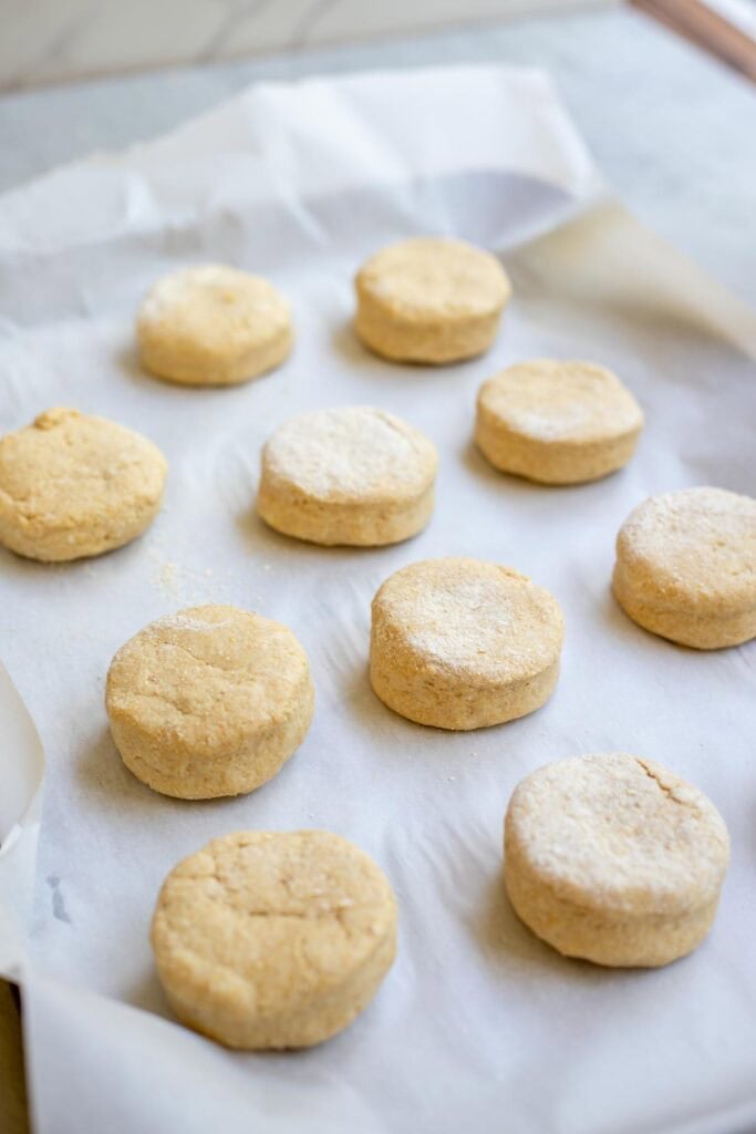 Raw biscuit dough on a parchment lined baking sheet.