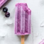one blueberry popsicle with a bite out of the top right corner.