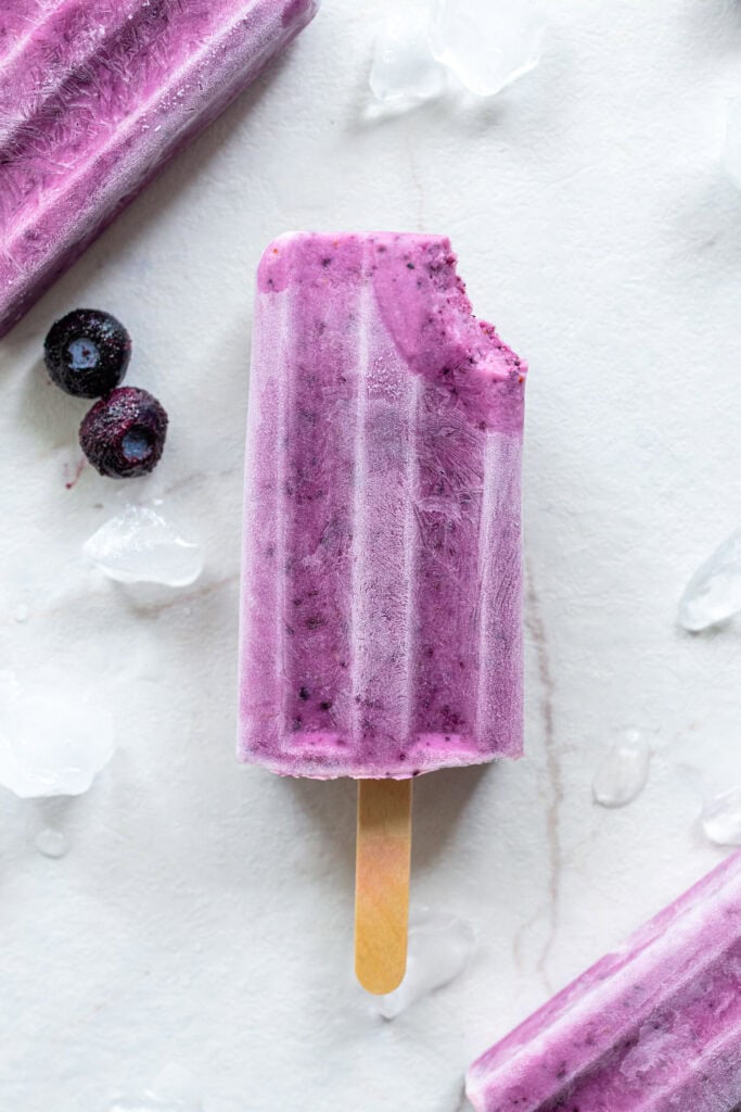 One blueberry popsicle with a bite out of the top right corner.