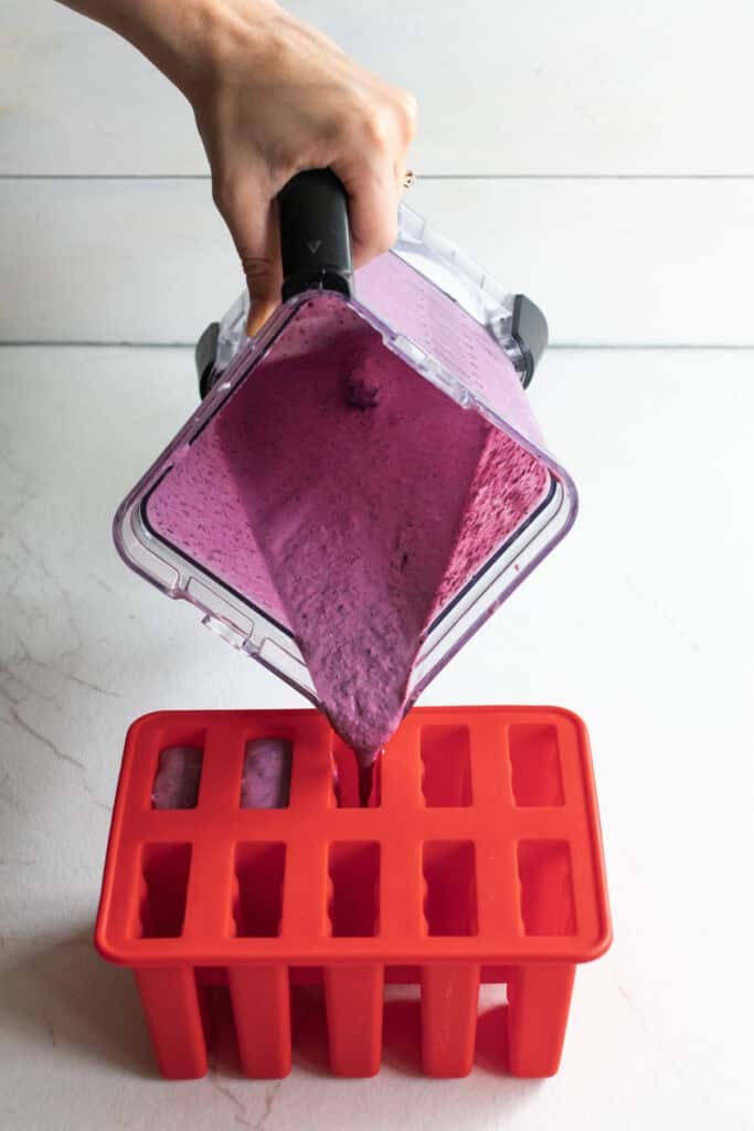 Pouring popsicle mixture into silicone molds.