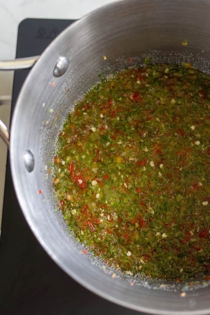 Jalapenos and bell peppers cooking in a large pot to become jelly.