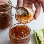 spreading jalapeno jelly on a cracker with cream cheese.