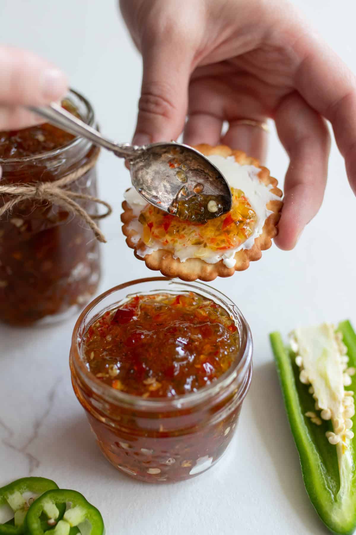 Spreading jalapeno jelly on a cracker with cream cheese.
