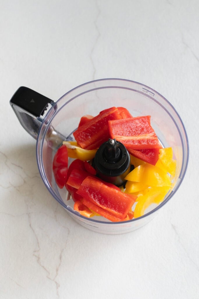Red and yellow bell peppers in a food processor.