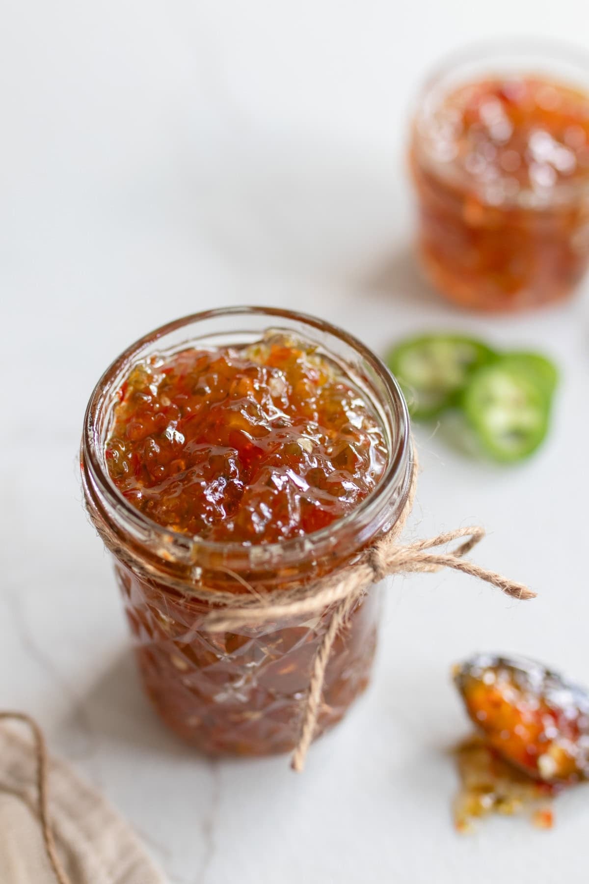 Pepper jelly in a glass jar on the countertop.