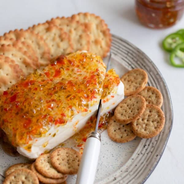 a block of cream cheese with jalapeno jelly spread over the top.