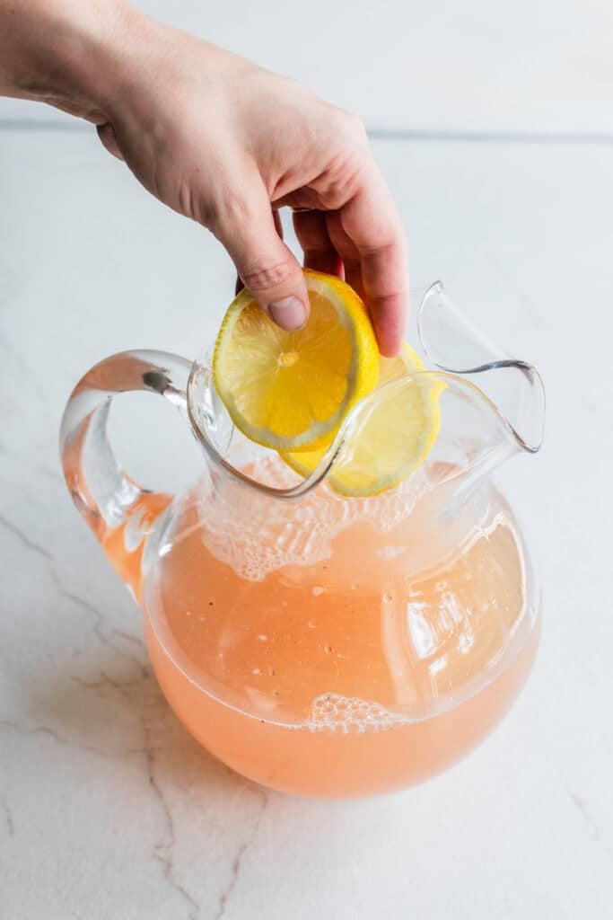 Adding lemons to a pitcher to make lemonade.