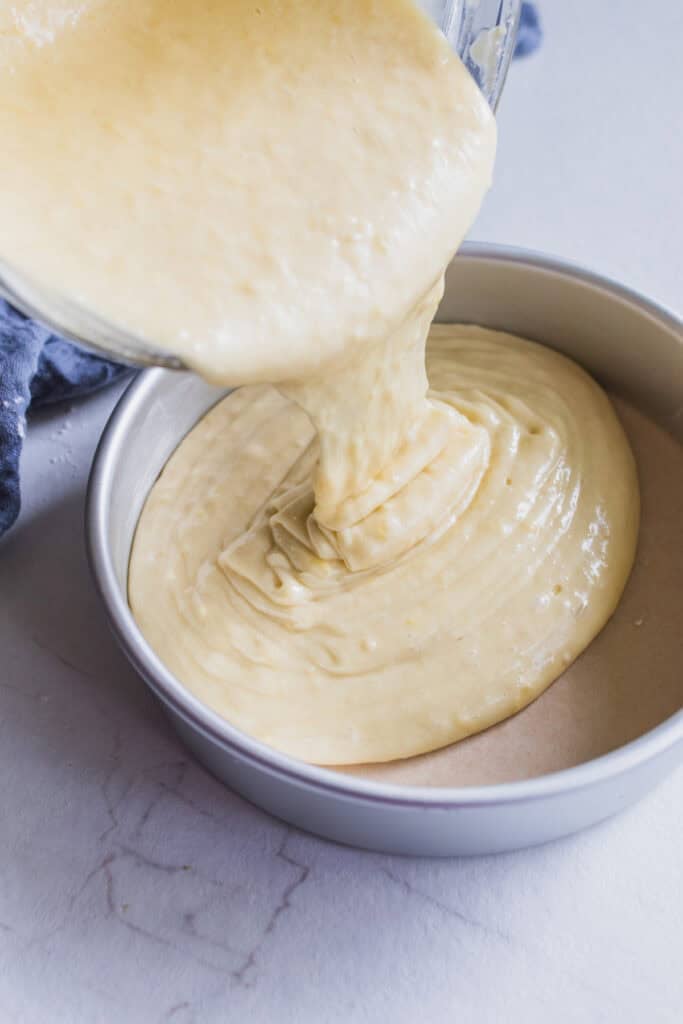 Pouring cake batter into a parchment lined round cake pan.