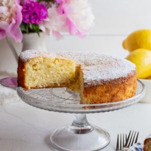 a slice of cake sitting on a glass cake plate.