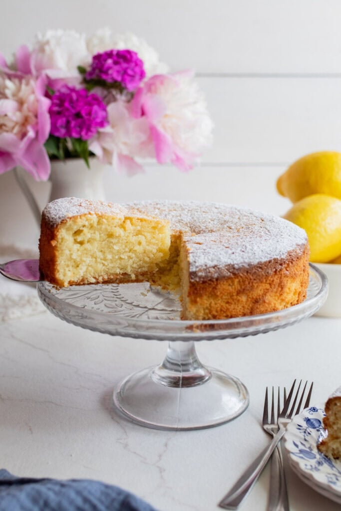a slice of cake sitting on a glass cake plate.
