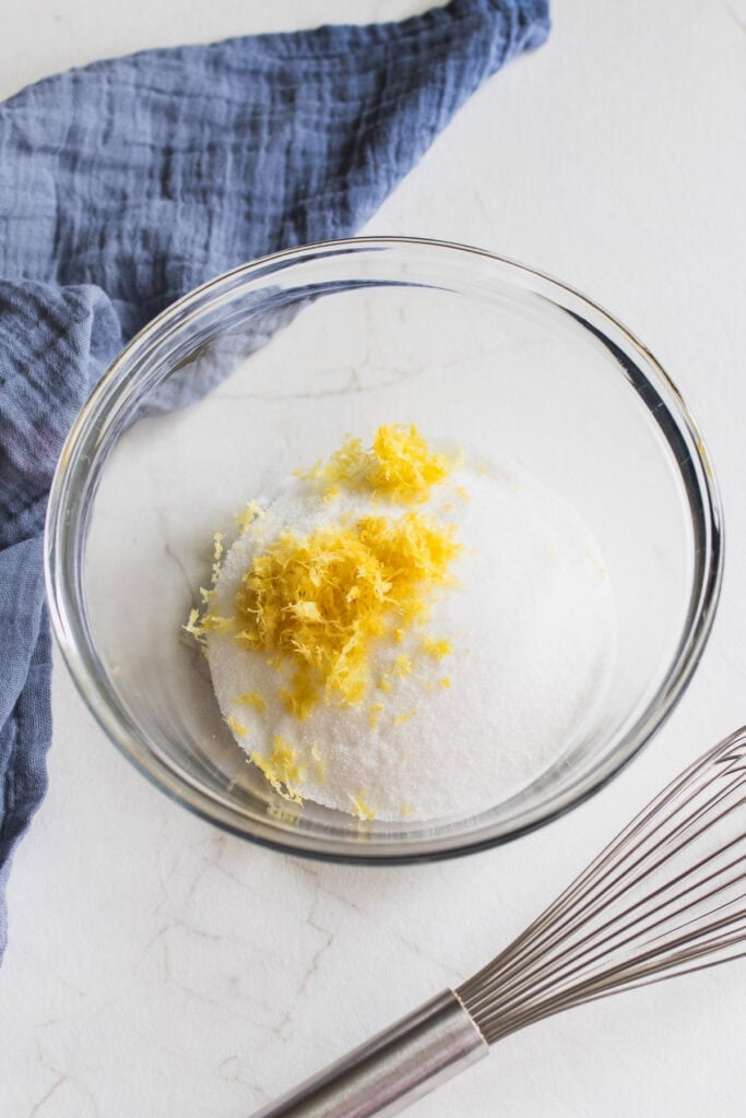 Sugar, almond extract, and lemon zest in a bowl.