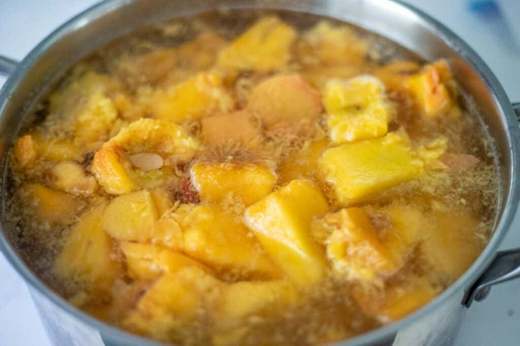 Chopped peaches simmering in a pot.