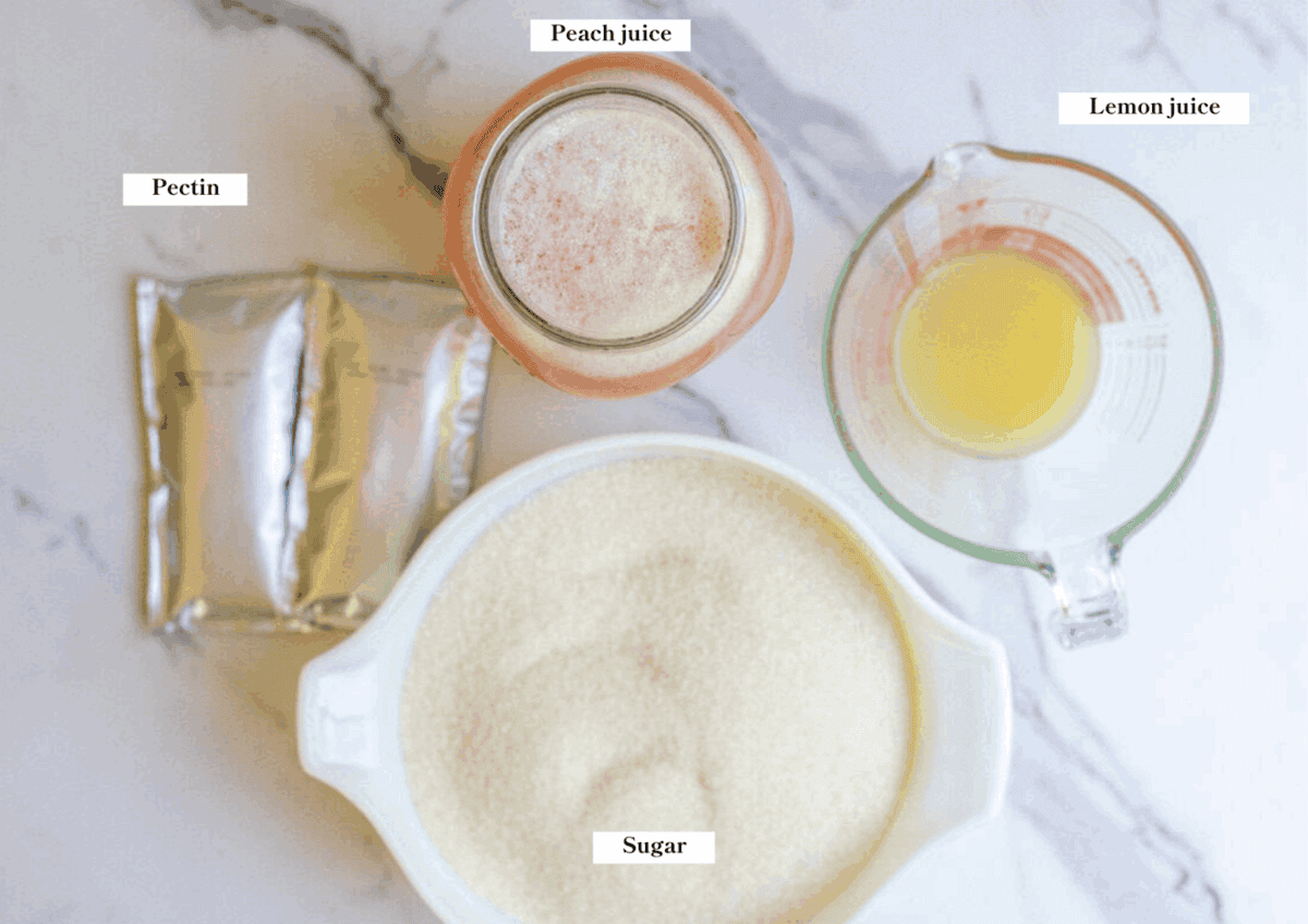 Sugar, peach juice, lemon juice, and pectin laying on a marble countertop.
