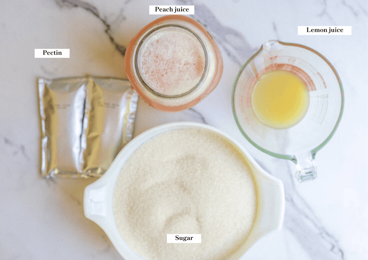 Sugar, peach juice, lemon juice, and pectin laying on a marble countertop.
