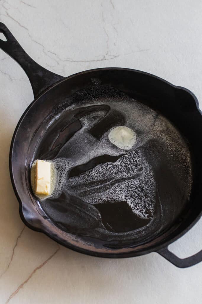 A cast iron skillet heating up with some butter.