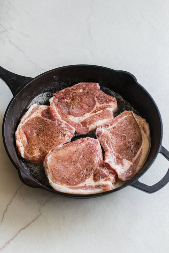 4 pork chops in a cast iron skillet.