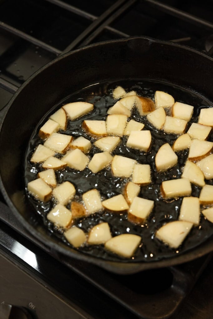 Potatoes cooking in a cast iron skillet.